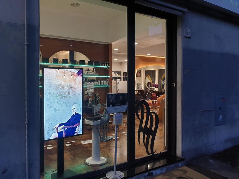 Display Samsung Smart Signage monitor tv installato nella vetrina del salone parrucchiere uomo donna