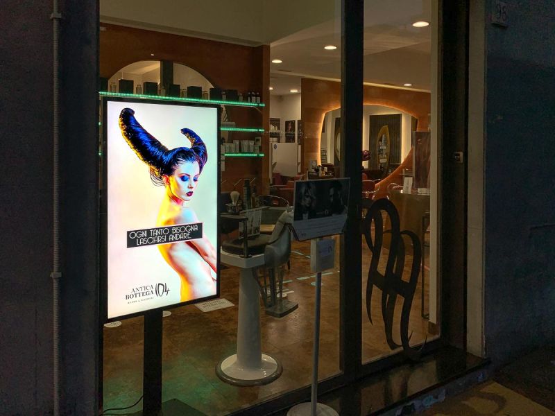 Display Samsung Smart Signage monitor tv installato nella vetrina del salone parrucchiere uomo donna