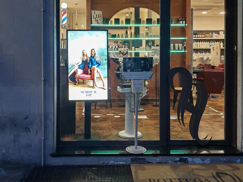 Display Samsung Smart Signage monitor tv installato nella vetrina del salone parrucchiere uomo donna