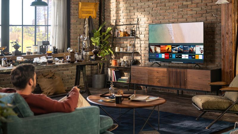 Uomo che guarda TV consumer Samsung nel salotto di casa